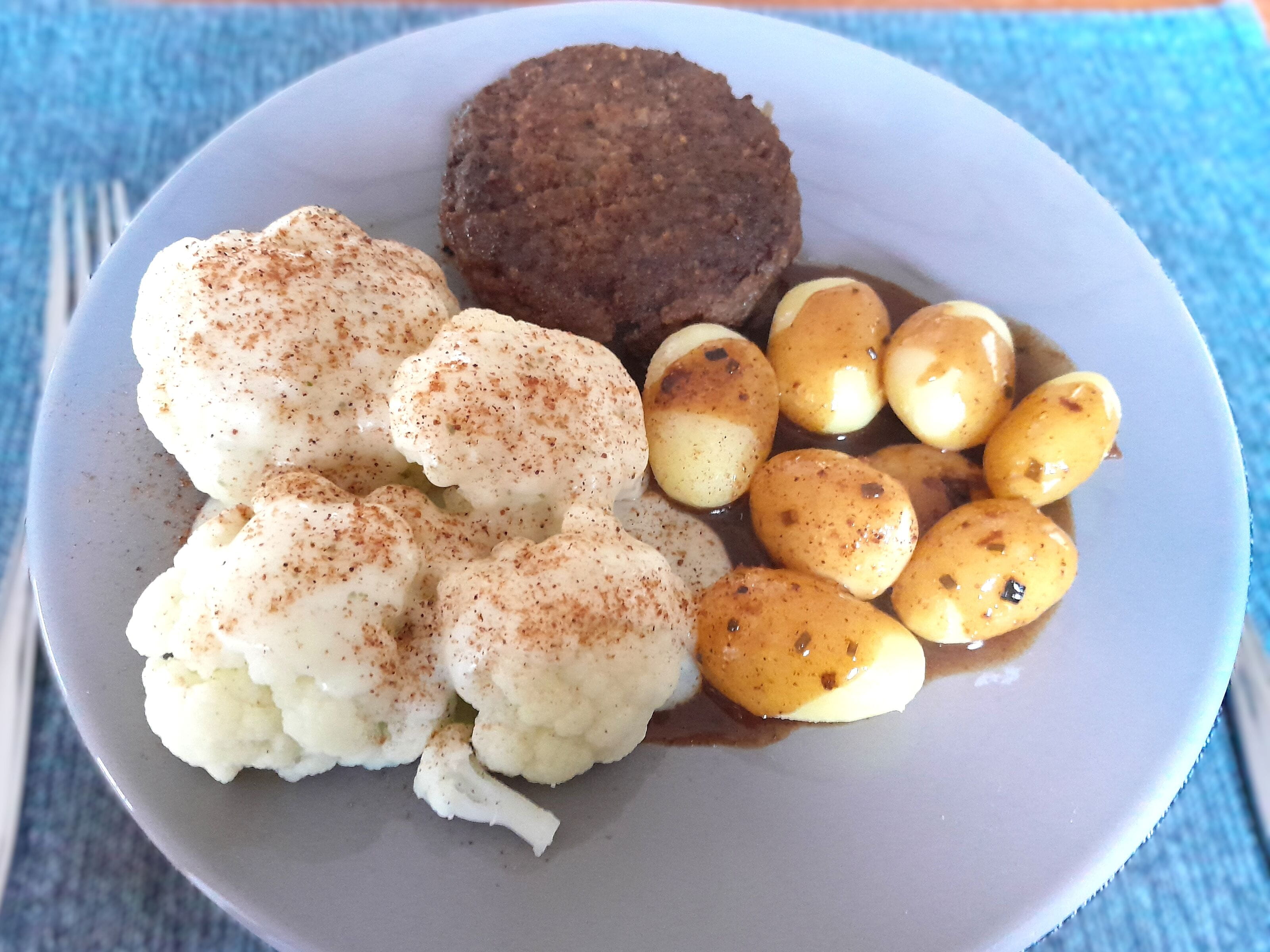 Bord met bloemkool, gehaktschijf en krieltjes.
